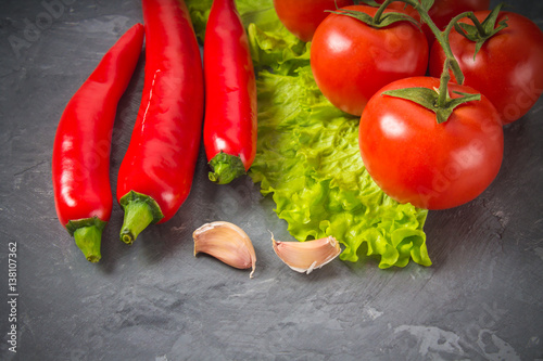 Red chili peppers, tomatoes, Sadat and garlic on a gray marble background. photo