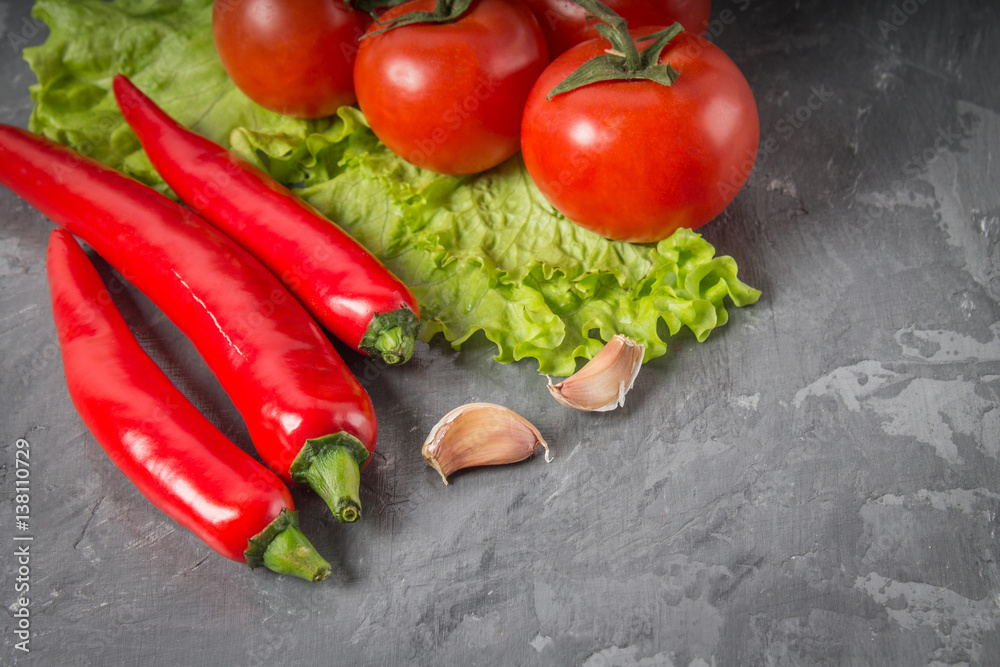 chili peppers, tomatoes, lettuce, garlic on a gray background. chili peppers, tomatoes, lettuce, garlic on a gray background.