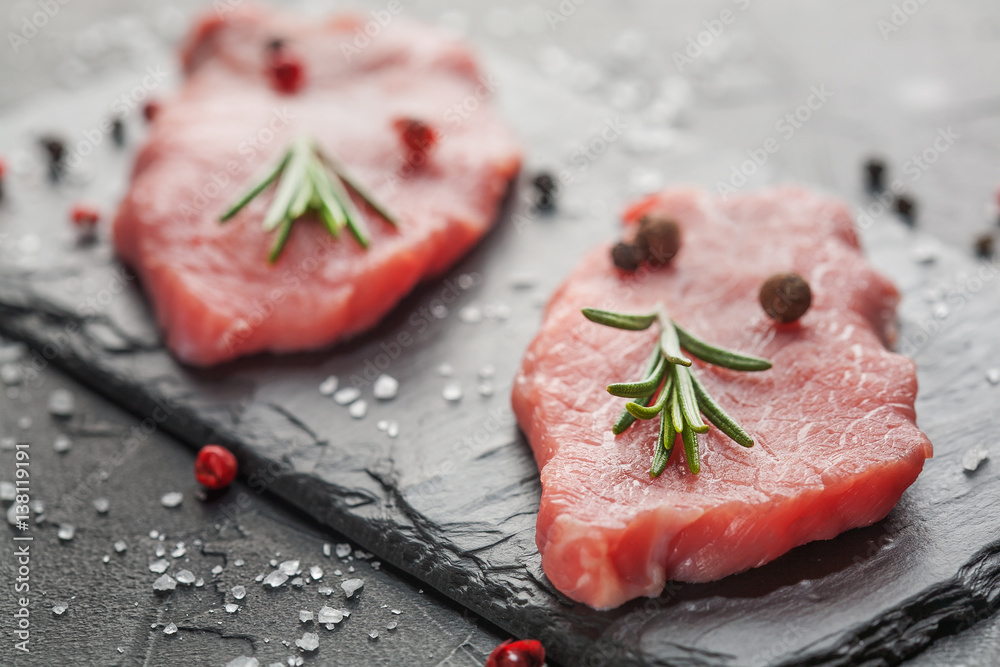 raw beef steak with rosemary and peppers on dark stone raw beef steak with rosemary and peppers on dark stone
