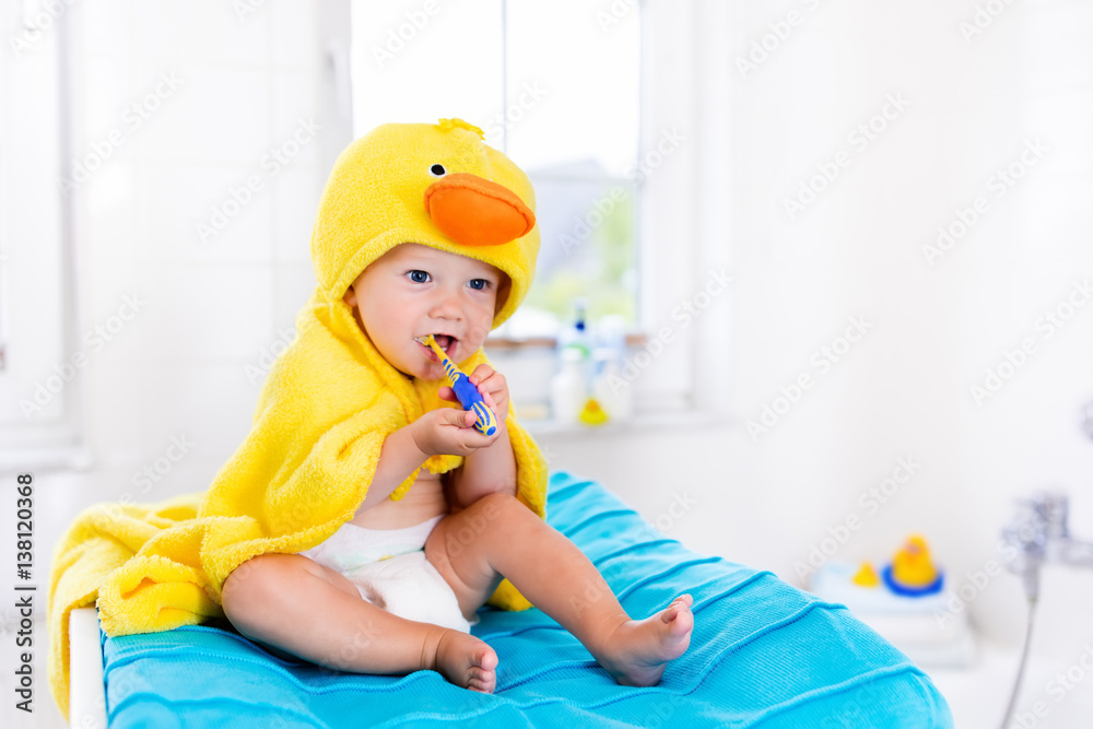 Baby in bath towel with tooth brush