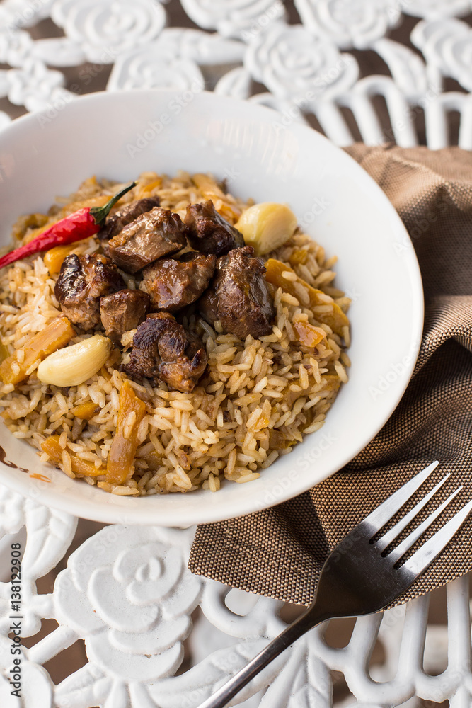 Pilaf - Rice with Meat and Vegetables on the table. Pilaf with lamb and garlic zira Pilaf - Rice with Meat and Vegetables on the table. Pilaf with lamb and garlic zira
