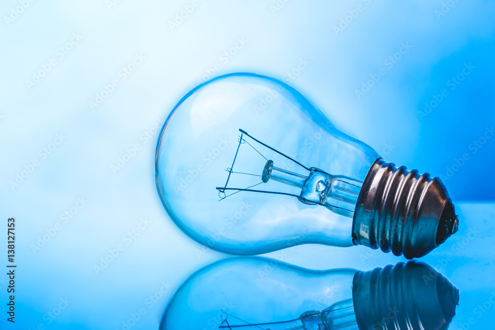 Light bulb on blue glossy reflective glass surface. Light bulb on blue glossy reflective glass surface.