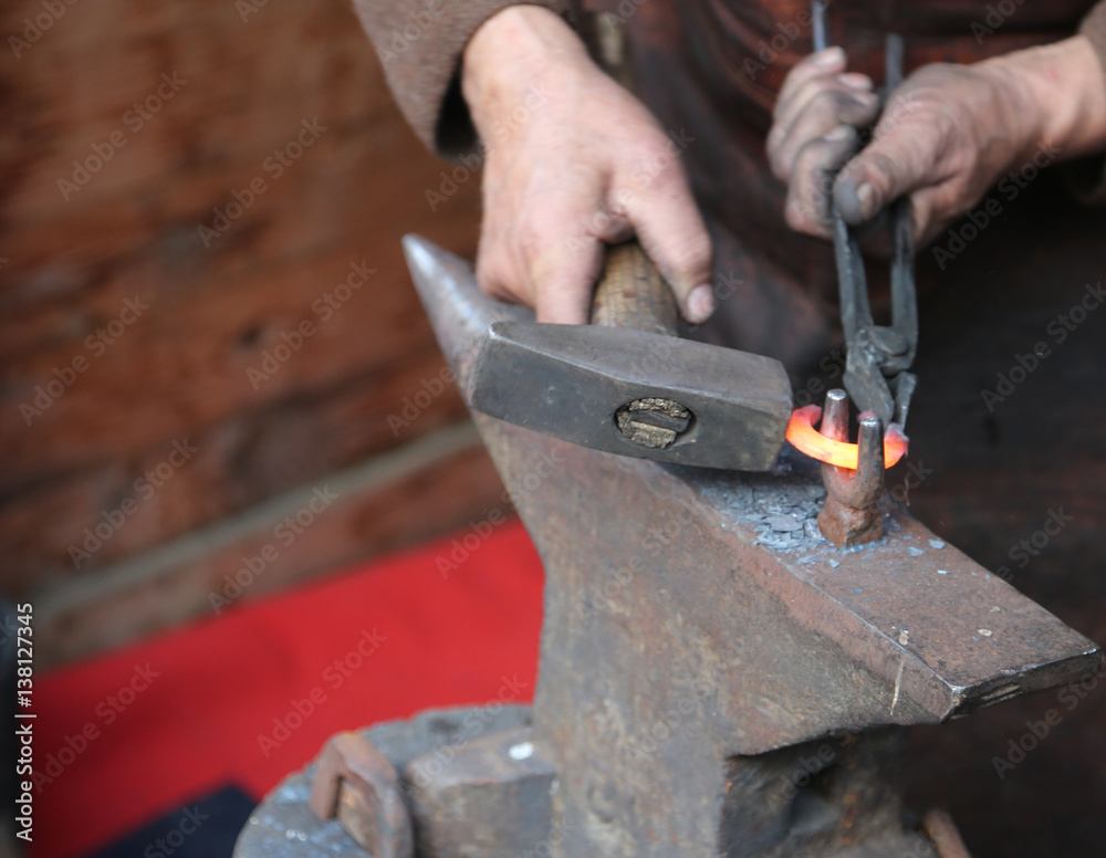 hand elder blacksmith who uses pliers to shape a hot iron hand elder blacksmith who uses pliers to shape a hot iron