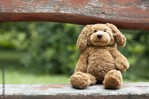 Childhood concept - cute vintage toy bear sitting on a bench