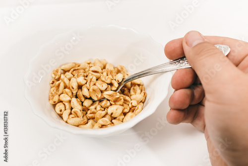 dry Breakfast in white plate on a white background (the human hand holds a spoon) photo