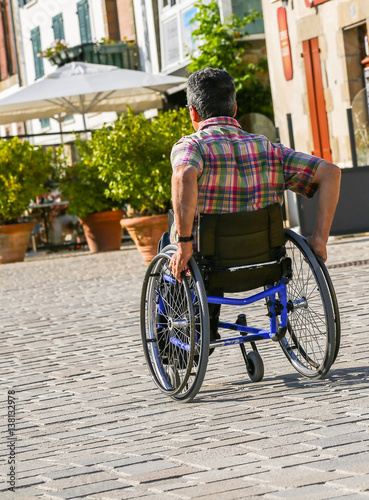 Disabled man rolling down the street in his wheelchair