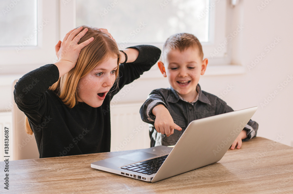 Suprised kids looking at laptop screen at home Suprised kids looking at laptop screen at home