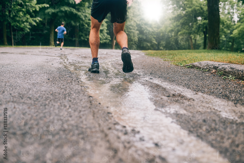 Fototapeta premium Muscular calves of fit male jogger training for cross country forest trail race in the rain on a nature trail.