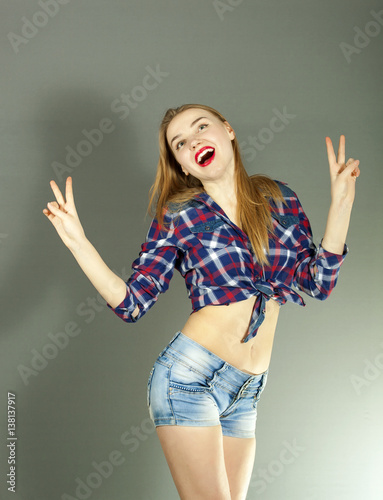 
Young smiling  emotion sexy girl in pinup stile show two  fingers  against gray background
 photo