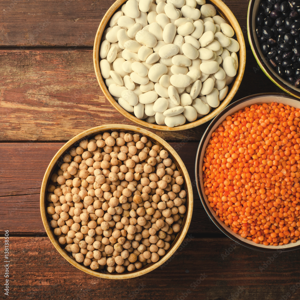 Assorted beans in bowls with red lentil, chick-pea and kidney bean on wooden background. Assorted beans in bowls with red lentil, chick-pea and kidney bean on wooden background.