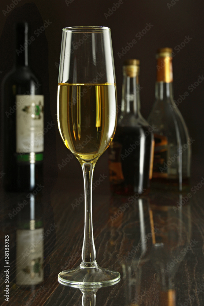 Glass of white wine on mirror table. bottles in a bar on the background Glass of white wine on mirror table. bottles in a bar on the background