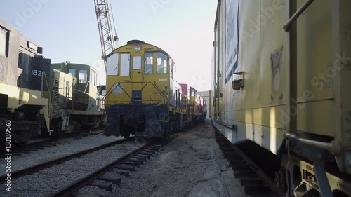 Old Diesel Train Reveal / Revealing an old historic yellow diesel train in a messy train yard. photo