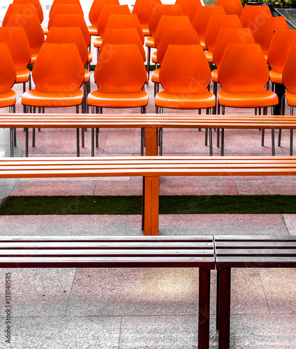 Red and orange Empty plastic chairs and Iron benches kept for people before a gathering photo