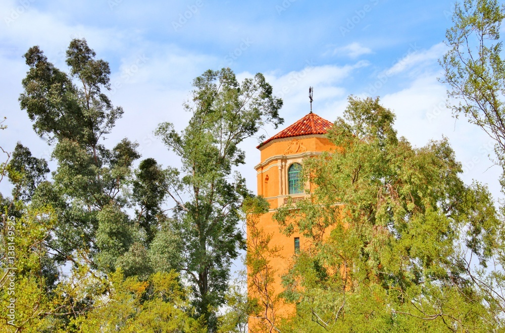 Hidden behind the trees and standing alone is a tower with beautiful architecture. Hidden behind the trees and standing alone is a tower with beautiful architecture.