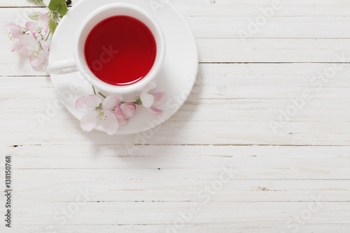 Red tea with flowers on white wooden background