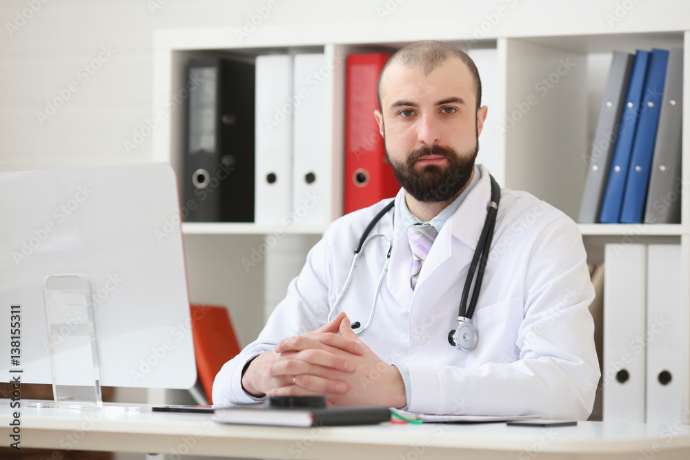 Doctor with a beard sitting at the desk in the office Doctor with a beard sitting at the desk in the office
