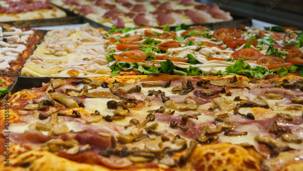 traditional italian pizza with various vegetables, mushrooms and meat at the window of italian pizzeria in Bergamo, Italy