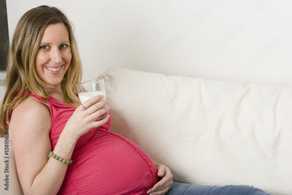 Expecting mother sitting on the sofa drinking milk. Expecting mother sitting on the sofa drinking milk.