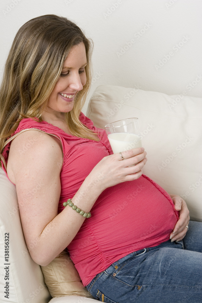 Expecting mother sitting on the sofa drinking milk. Expecting mother sitting on the sofa drinking milk.