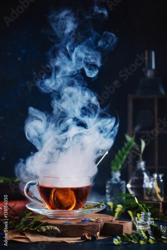 Glass cup of steaming tea with herbs