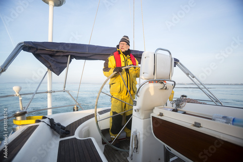 Man Steering Wheel Of Yacht In Sea