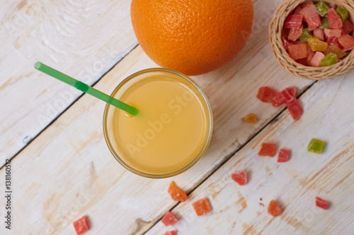 A whole orange with a glass of orange juice on a white wooden background. View from above.