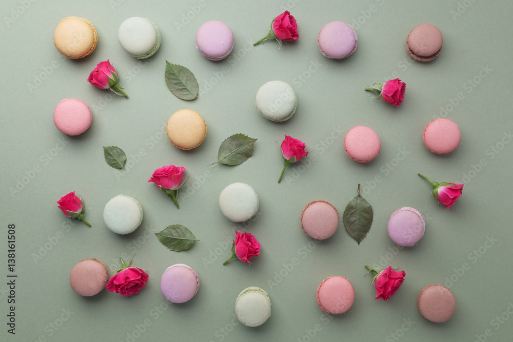 Macarons flat lay withroses and leaves on green background. Top view Macarons flat lay withroses and leaves on green background. Top view