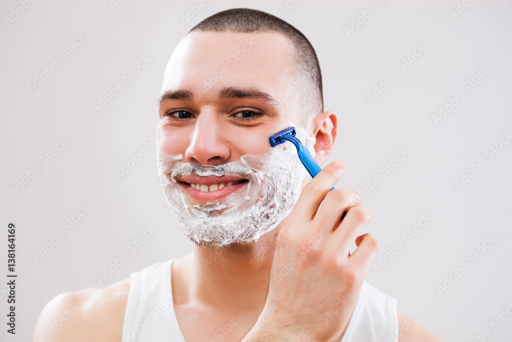 Young man is shaving his beard.