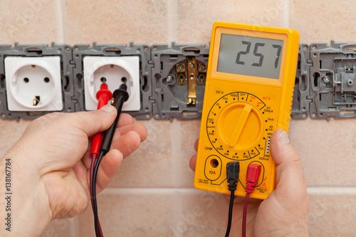 Electrician checking voltage in a partially installed electrical wall socket