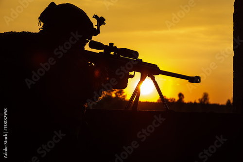 Army sniper with large-caliber sniper rifle seeking killing enemy. Silhouette on sky background. National security ensured, servicemen on guard