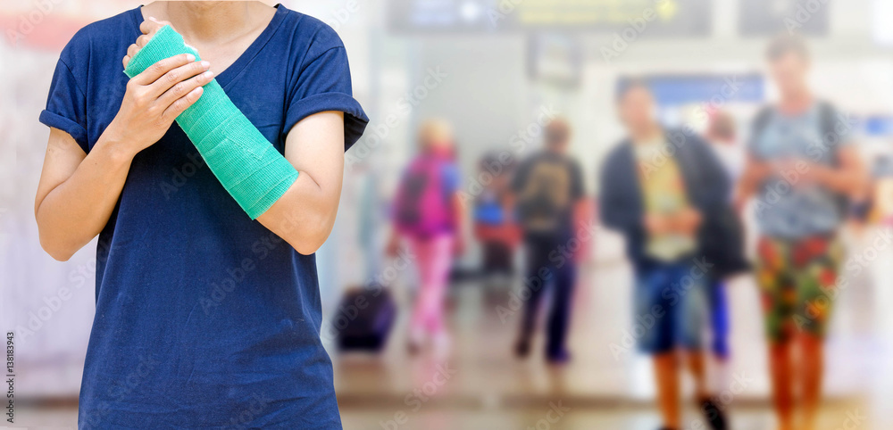 accident on arm, Injured woman with green cast on hand and arm on traveler in motion blur in airport interior background, ,body injury concept