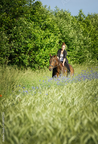 Reiten in der Natur - Teenager reitet mit Pferd über einen Feldweg