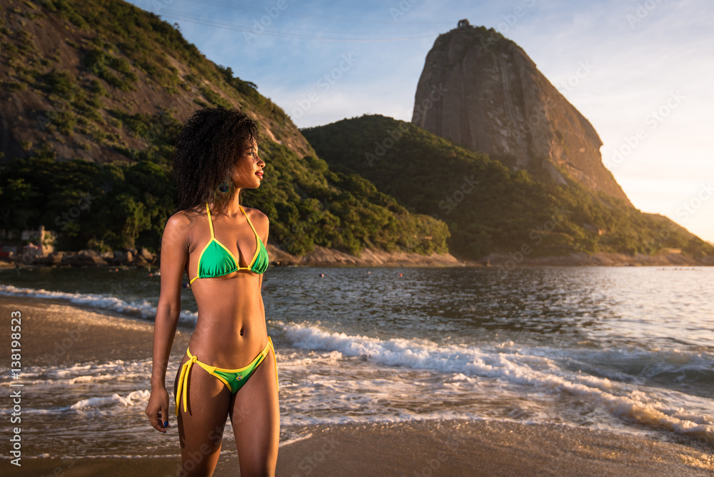 Young Beautiful Brazilian Woman in Bikini Walking at the Beach by Sunrise  With the Sugarloaf Mountain in the Background, in Rio de Janeiro Stock  Photo