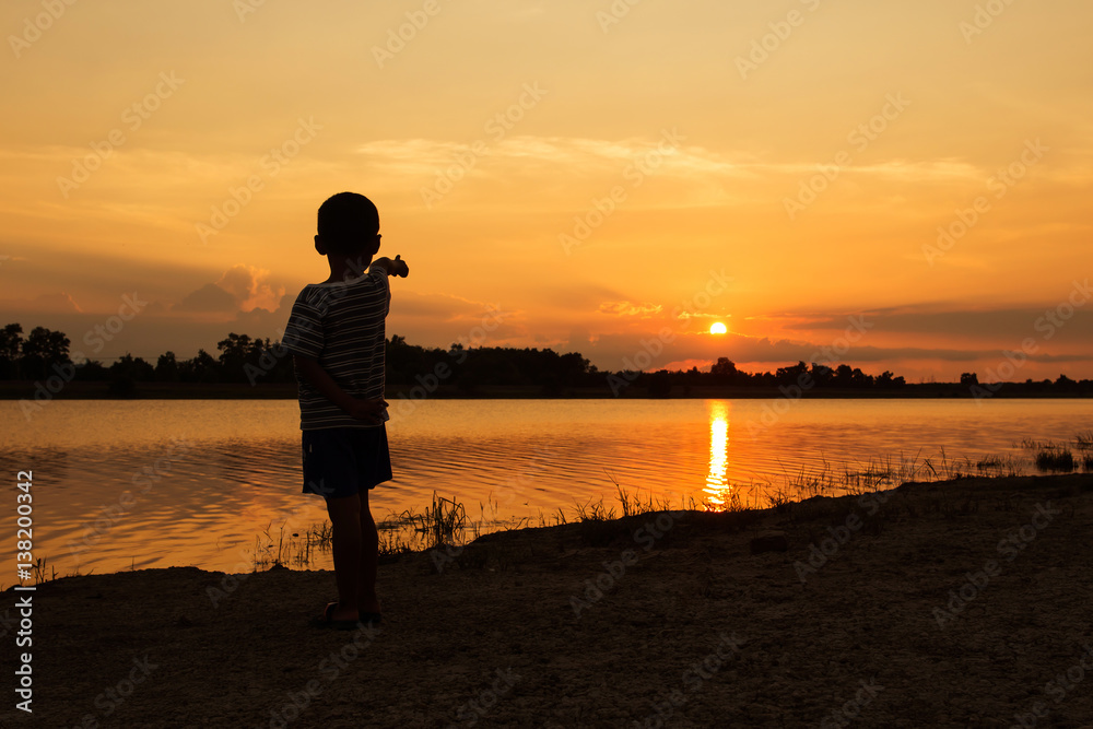 Cute little boy play at river sunset background