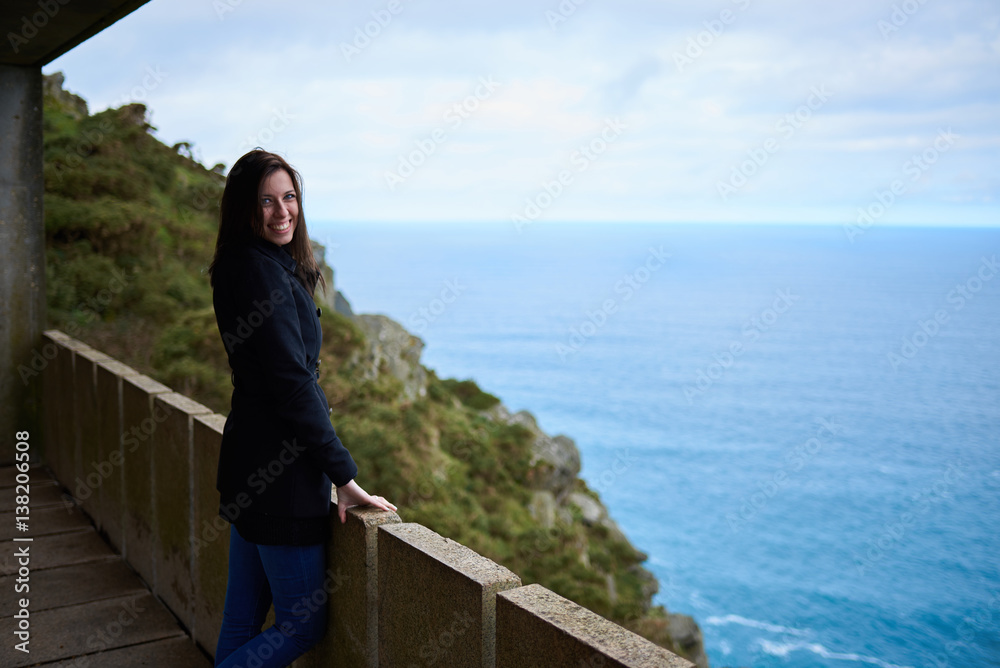 Mujer joven sonriendo en un mirador hacia el mar Mujer joven sonriendo en un mirador hacia el mar