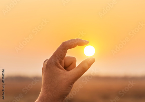 Fotografie, Tablou Silhouette catch holding the sun in fingers