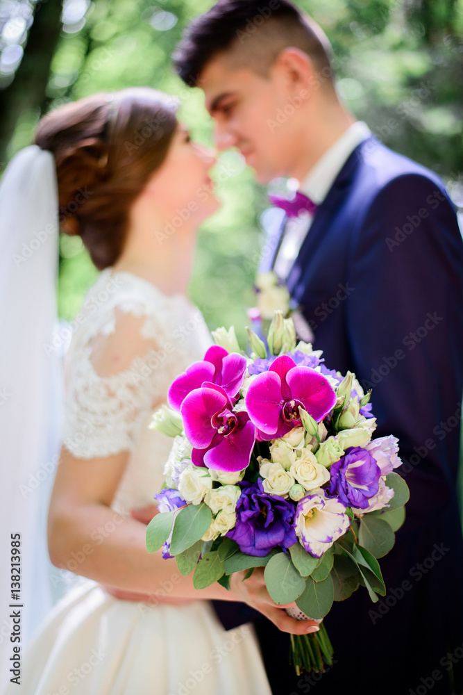Close-up of colorful wedding bouquet held by hugging wedding couple Close-up of colorful wedding bouquet held by hugging wedding couple