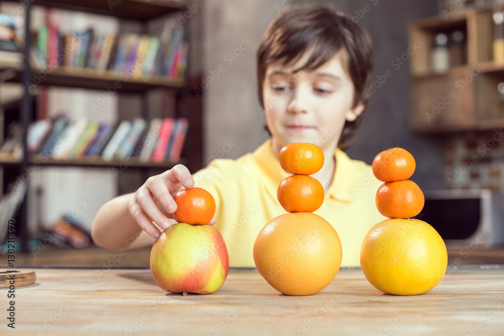 Cute little boy playing with fresh fruits on table Cute little boy playing with fresh fruits on table