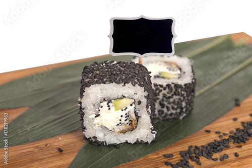 Tableau sur toile Sushi rolls on wooden Board with leaves of leeks and black sign for logo and nam