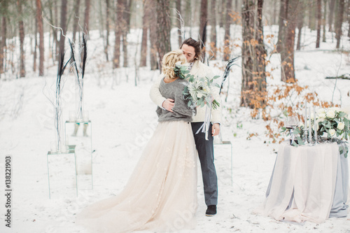 Beautiful stylish couple kissing in the winter park outside