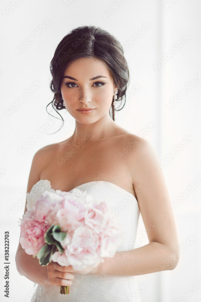 Beautiful brunette woman as bride with pink wedding bouquet on white