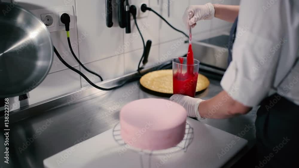 The girl mixes red icing for the cake. The girl mixes red icing for the cake.