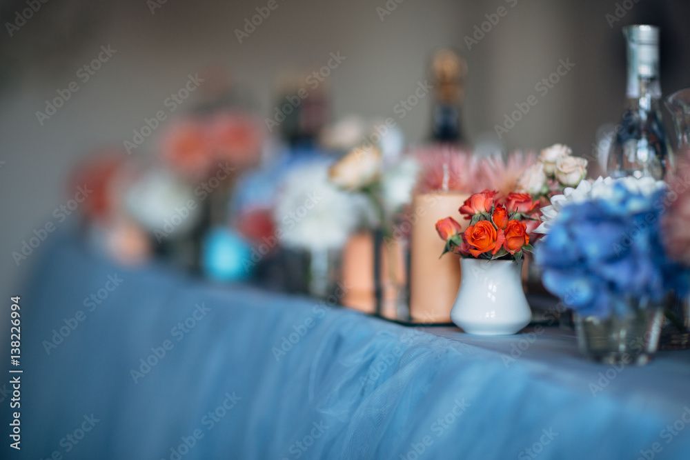 The candles and vases with flowers  stand on the wedding table