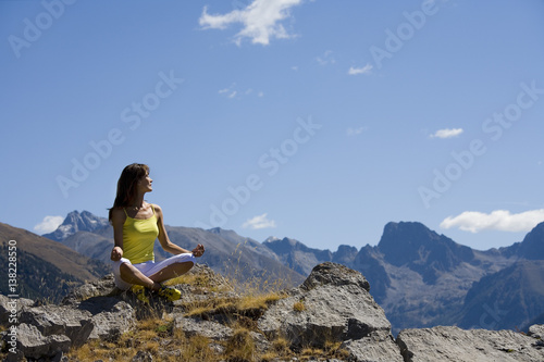femme qui se relaxe en faisant du yoga au sommet d'une montagne