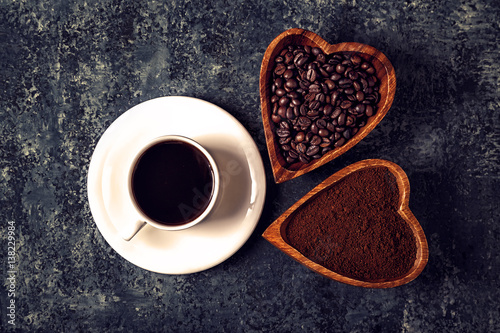 Coffee cup, beans and ground powder on stone background. 