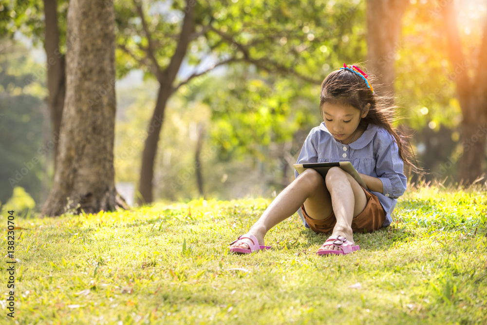 Little girl using computer tablet or smartphone in park Little girl using computer tablet or smartphone in park