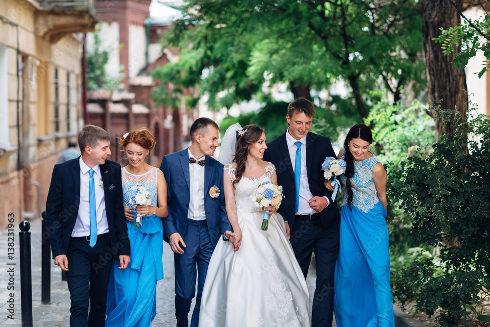 The brides,bridesmaids and groomsmen walking along street The brides,bridesmaids and groomsmen walking along street