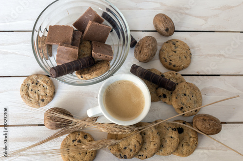 Cup of coffee, cookies, walnut and chocolate on the white wooden background