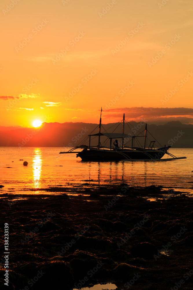 Sunset over a tropical asian island with a local boat in the foreground Sunset over a tropical asian island with a local boat in the foreground