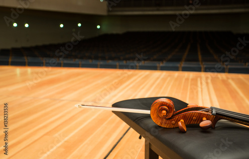 a pegbox of cello with a bow in empty concert hall